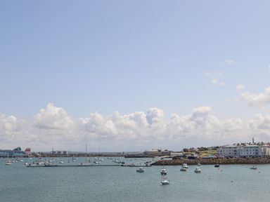 A harbor with boats anchored in the water and buildings along the shore at Glasfryn in Holyhead