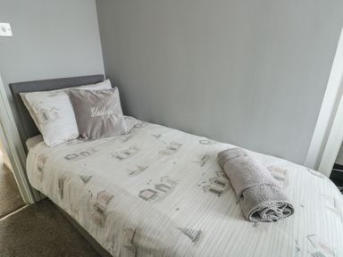 A bedroom with a single bed and towel at Glasfryn in Holyhead