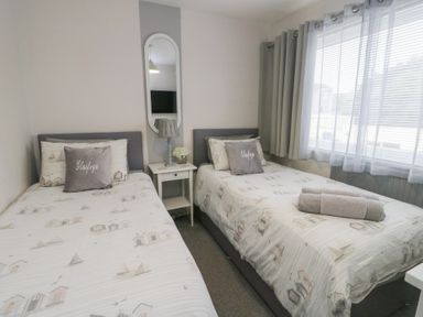 A bedroom with two single beds and a bedside table at Glasfryn in Holyhead