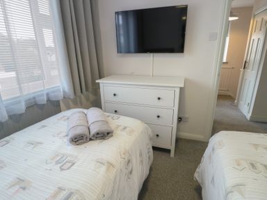 A bedroom with two beds and a television at Glasfryn Holyhead