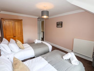 A bedroom with two single beds a wooden wardrobe and a framed picture on the wall at Oakhurst in Keswick
