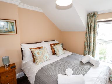 A bedroom with a double bed with pillows and rolled towels near a window with curtains at Oakhurst in Keswick