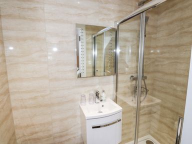A bathroom with a small white sink cabinet under a mirror and a glass shower enclosure at Oakhurst in Keswick