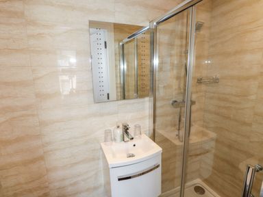 A bathroom with a sink and mirror and a glass enclosed shower at Oakhurst in Keswick
