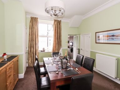 A dining room with a wooden table set for six chairs and a sideboard at Oakhurst in Keswick