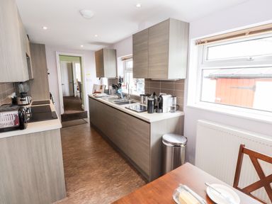 A kitchen with wooden cabinets a countertop with appliances and a dining table at Oakhurst in Keswick
