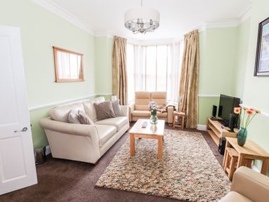 A living room with beige sofas a wooden coffee table and a television at Oakhurst in Keswick