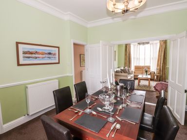 A dining room with a set table and black chairs next to a living room with sofas and a coffee table at Oakhurst in Keswick