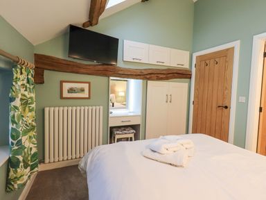 A bedroom with a bed towel and wardrobe against a green wall at Old Howgate Barn Outgate near Hawkshead