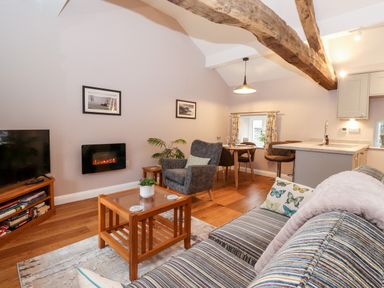 A living room with a striped sofa armchair coffee table and TV at Low Ashmead Cottage in Hawkshead