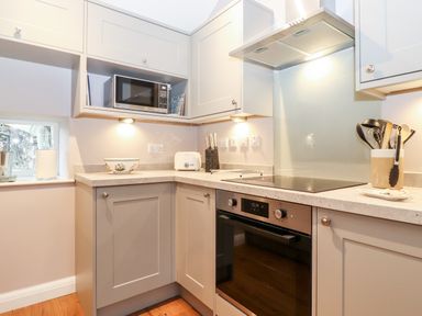 A kitchen corner with cabinets a microwave oven toaster knives and cooking utensils at Low Ashmead Cottage in Hawkshead