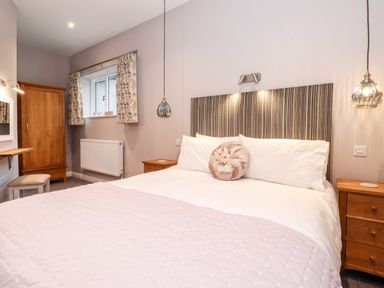 A bedroom with a double bed bedside tables hanging lights and a wardrobe at Low Ashmead Cottage in Hawkshead