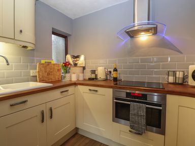 A kitchen corner with cabinets a sink a stove oven and countertop items at Rayside Ullswater
