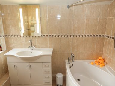 A bathroom with a white sink cabinet mirror and a bathtub with rubber ducks at Rayside Ullswater