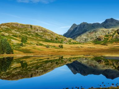 A mountain landscape with a clear lake reflecting the hills and sky at Rayside in Ullswater