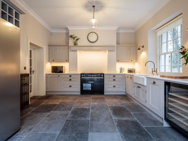 A kitchen with gray cabinets a black stove a refrigerator and a large window at The Vicarage near Rosthwaite