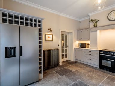 A kitchen with a double door refrigerator framed by shelving a stove microwave and a radiator near The Vicarage near Rosthwaite
