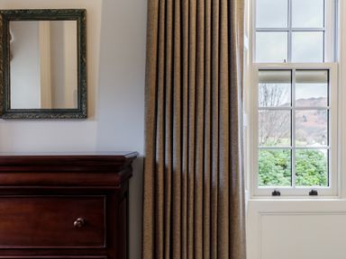 A wooden dresser under a mirror next to a window with closed curtains at The Vicarage near Rosthwaite