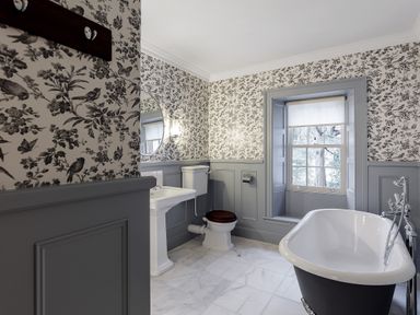 A bathroom with a freestanding bathtub toilet and sink under a window at The Vicarage near Rosthwaite