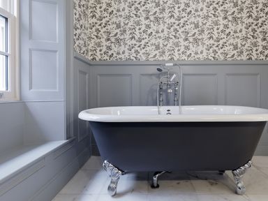 A bathroom with a freestanding clawfoot bathtub a window and floral wallpaper at The Vicarage near Rosthwaite