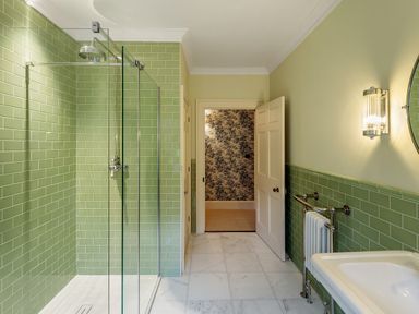 A bathroom with green tiled walls a glass shower door a white sink and marble floor at The Vicarage near Rosthwaite
