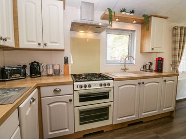 A kitchen with a stove kettle toaster coffee machine and sink at Lakeland Dream @ South Lakeland Leisure Lodge in Warton