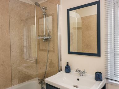 A bathroom with a bathtub shower combo a sink with a faucet and a mirror above at Lakeland Dream @ South Lakeland Leisure Lodge in Warton
