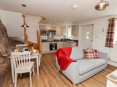 A kitchen and living area with gray sofa and dining table with chairs at The Old Mill Bake House in Goodrich