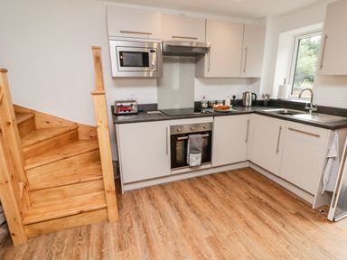 A kitchen with wooden stairs white cabinets a microwave oven toaster kettle and sink at The Old Mill Bake House in Goodrich