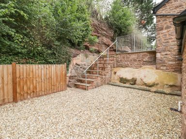 A gravel courtyard with wooden fence stone stairs and stone walls at The Old Mill Bake House in Goodrich