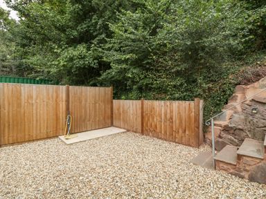 An outdoor area with gravel ground wooden fencing and stone steps with metal railing at The Old Mill Bake House in Goodrich