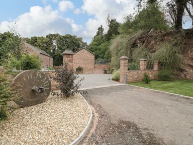 An outdoor entrance area with stone pillars gravel driveway stone buildings and greenery at The Old Mill Bake House in Goodrich