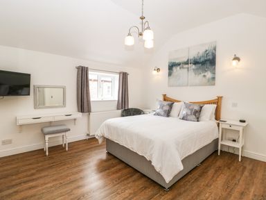 A bedroom with a double bed white bedding decorative pillows wooden headboard bedside tables wall art and a TV at The Old Mill Bake House in Goodrich