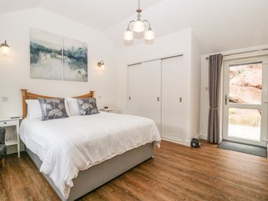 A bedroom with a double bed, two bedside tables, a closet with sliding doors, and a glass door with curtains at The Old Mill Bake House in Goodrich