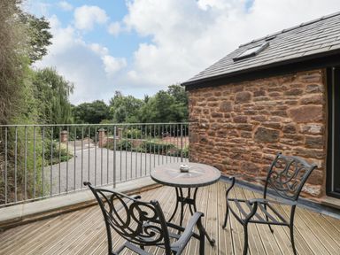 A patio with iron chairs and a round table next to a stone wall at The Old Mill Bake House in Goodrich