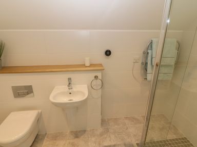 A bathroom with a toilet sink towel rack and shower area at 3 Lon Y Dryw in Trearddur Bay