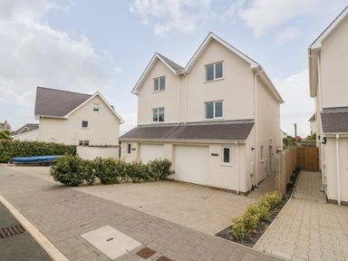 Two attached modern beige houses with garages and paved driveways in a residential area at 3 Lon Y Dryw in Trearddur Bay