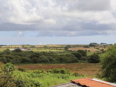 A rural landscape with fields and trees under a cloudy sky at The Hayloft in Helston