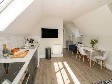 A kitchen with a countertop and sink and a dining table with chairs and flowers at Coach House Mews in Alderminster