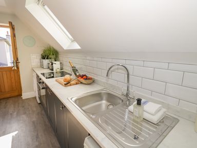 A kitchen with a sink stove fruit bowl and an open door at Coach House Mews in Alderminster