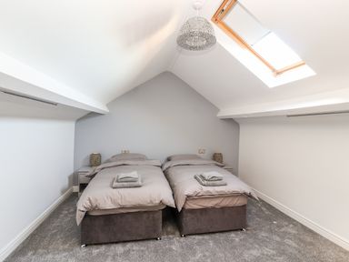 A bedroom with two single beds under a slanted ceiling with a skylight window at Lluest in Beaumaris