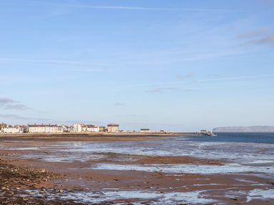 A coastal town with houses along the shore and a pier extending into the sea at Lluest in Beaumaris