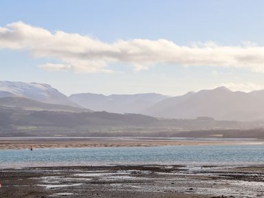 A coastal landscape with water and mountains in the background at Lluest in Beaumaris