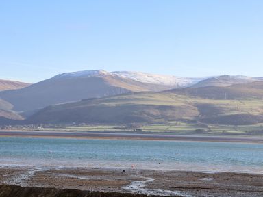 A coastal view with a sandy shore water and hills in the background at Lluest in Beaumaris
