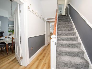 A hallway with carpeted stairs and a dining room visible through an open door at Lluest in Beaumaris
