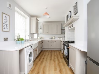 A kitchen with cabinets a washing machine stove sink and countertop at Lluest in Beaumaris