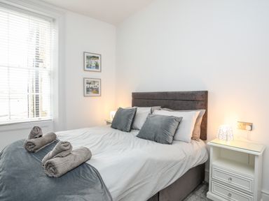 A bedroom with a double bed bedside tables and a window with blinds at Lluest in Beaumaris