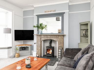 A living room with a fireplace TV sofa and coffee table at Lluest in Beaumaris