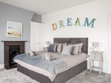 A bedroom with a large bed and pillows and a decorative word dream on the wall at Lluest in Beaumaris
