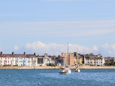A waterfront view with boats on the water and a row of houses along the shore at Lluest in Beaumaris